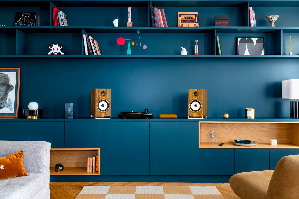 White speakers and a turntable on a blue sideboard
